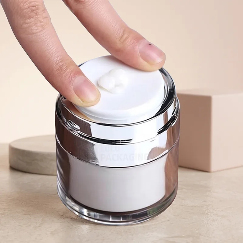 Finger pressing the pump plate of a silver airless jar with cream on top