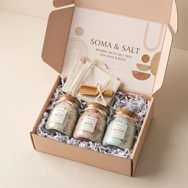 Pink bath salt mailer box with three corked jars, a wooden scoop and muslin bags