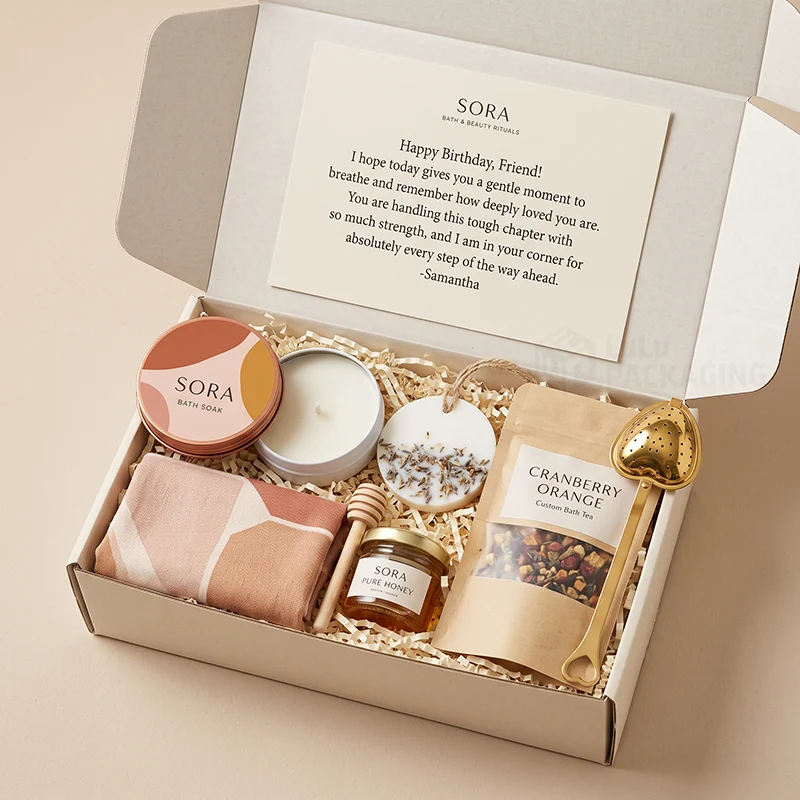White mailer box with a bath tea pouch, candle, soak tin, honey and a greeting card