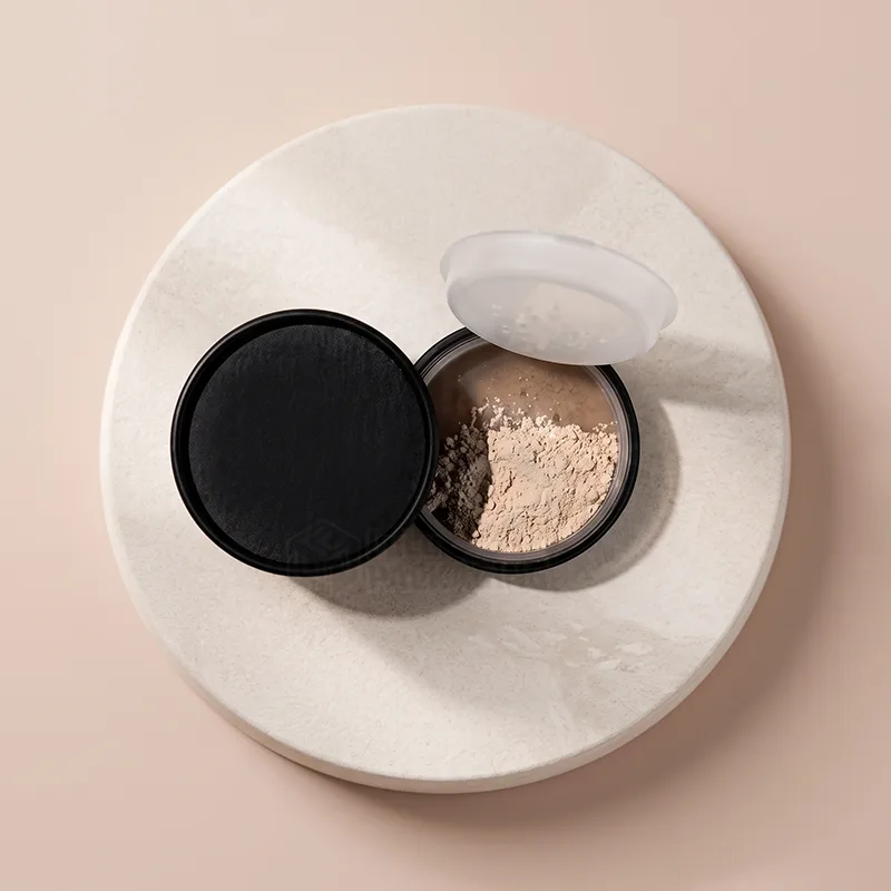 Top view of an open black loose powder jar filled with beige powder beside its lid