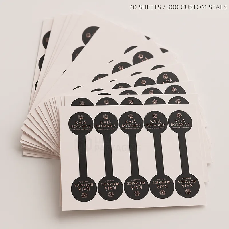 Fanned stack of sheets with black and rose gold dumbbell-shaped seal stickers for product closures