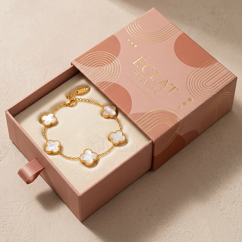 Pink drawer bracelet box with gold foil arches and a clover charm bracelet inside