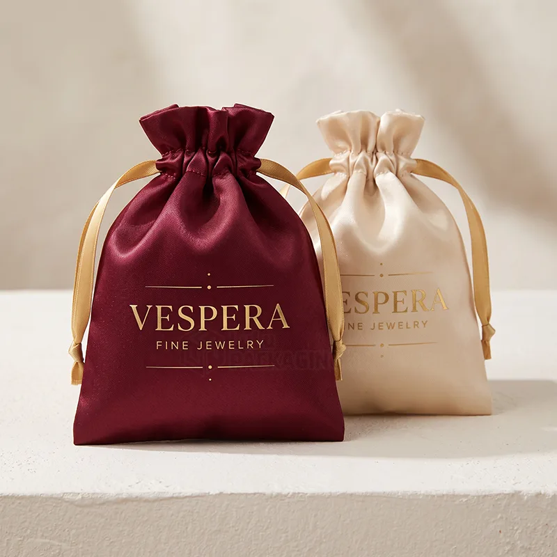 Burgundy and champagne satin jewellery pouches with gold ribbon drawstrings and a gold logo