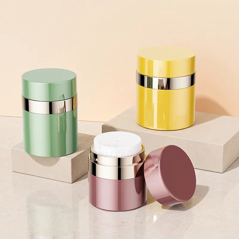 Green, yellow and rose airless jars with shiny silver bands, one open showing the pump
