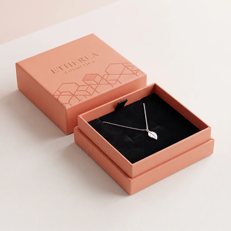 Coral two-piece necklace box with an embossed lid and a leaf pendant on black velvet