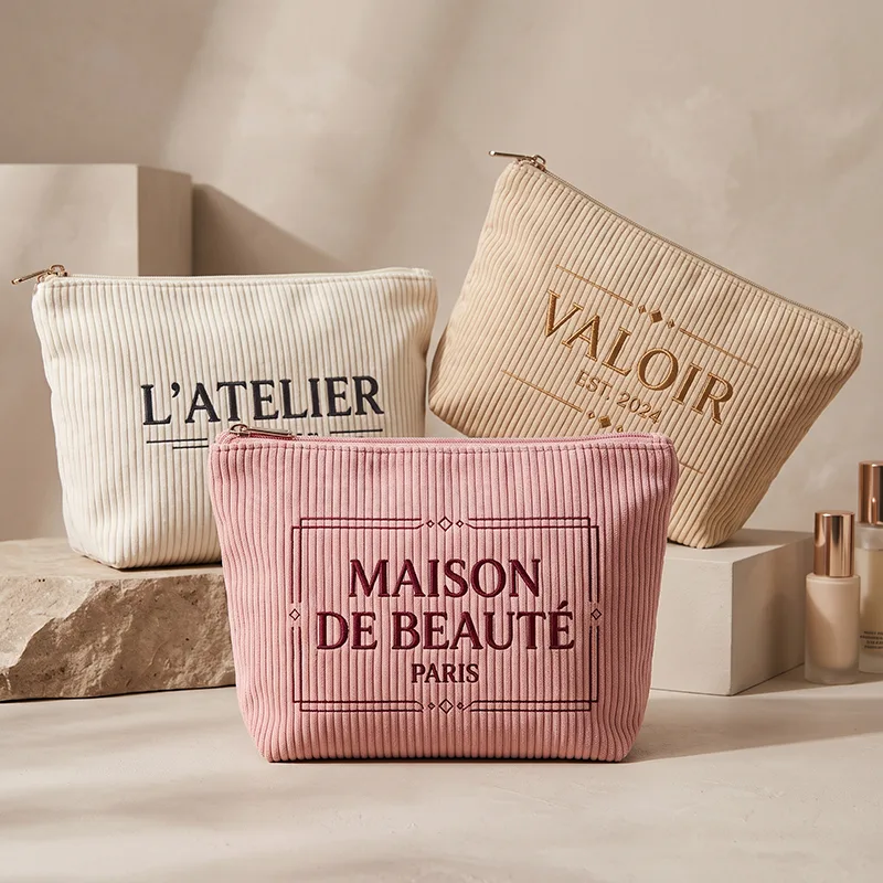 Cream, beige and pink corduroy makeup bags with embroidered logos