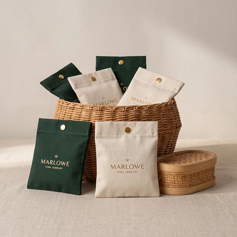 Green and natural cotton canvas jewellery pouches with gold snap buttons in a rattan basket