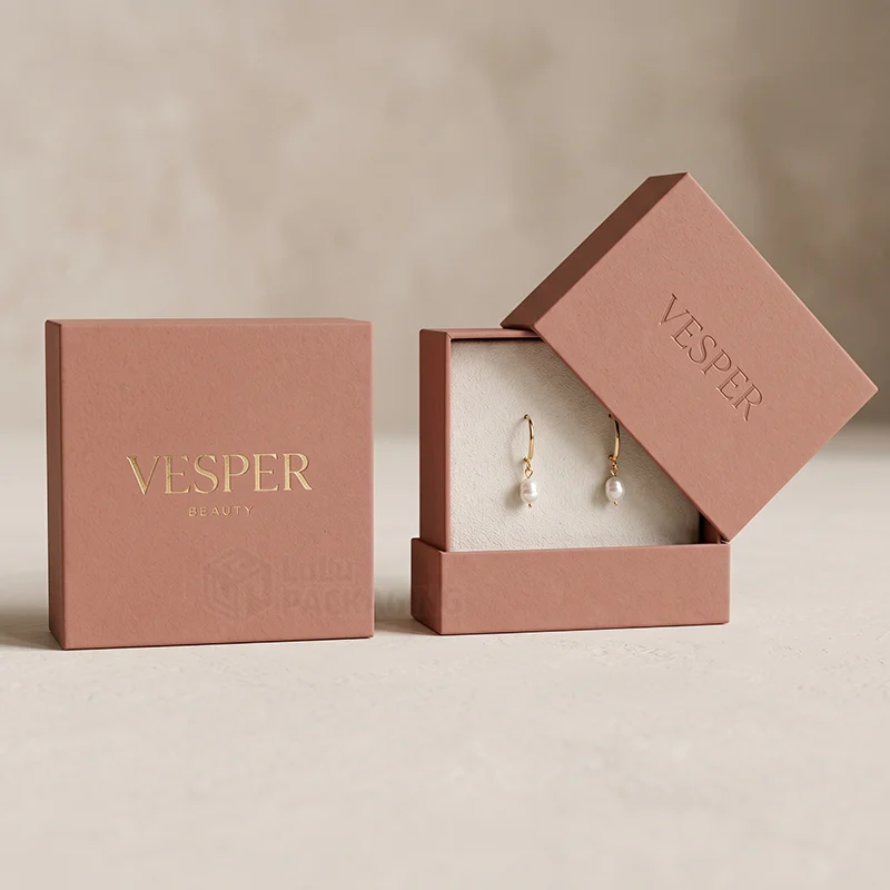 Two terracotta earring boxes with a gold foil logo, one open showing pearl drop earrings