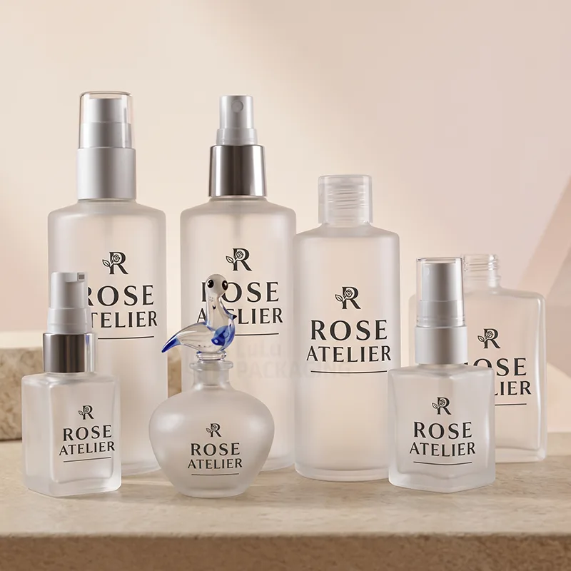 Frosted glass bottles in different sizes and shapes with silver pumps, sprayers and a glass stopper