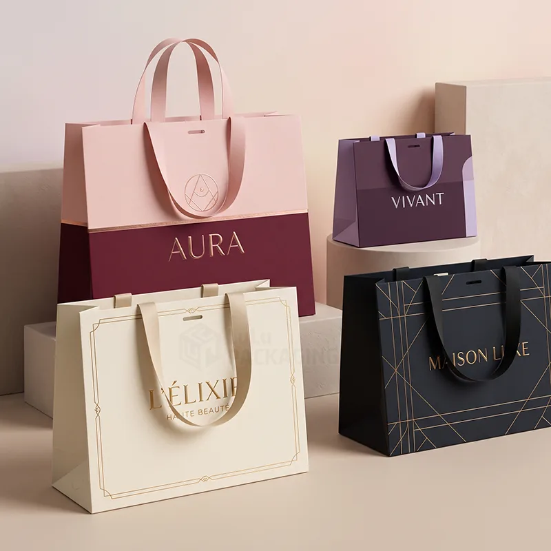 Four luxury paper gift bags in pink, purple, cream and black with ribbon handles and gold foil logos