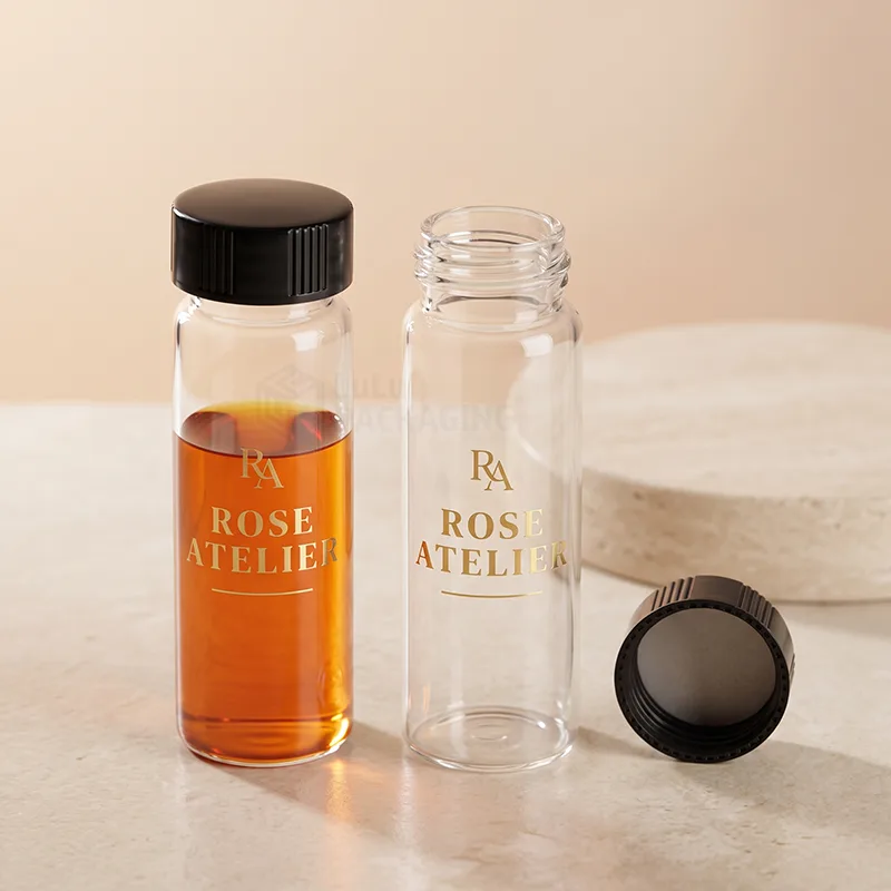Two clear glass sample vials with black screw caps and gold printed logos