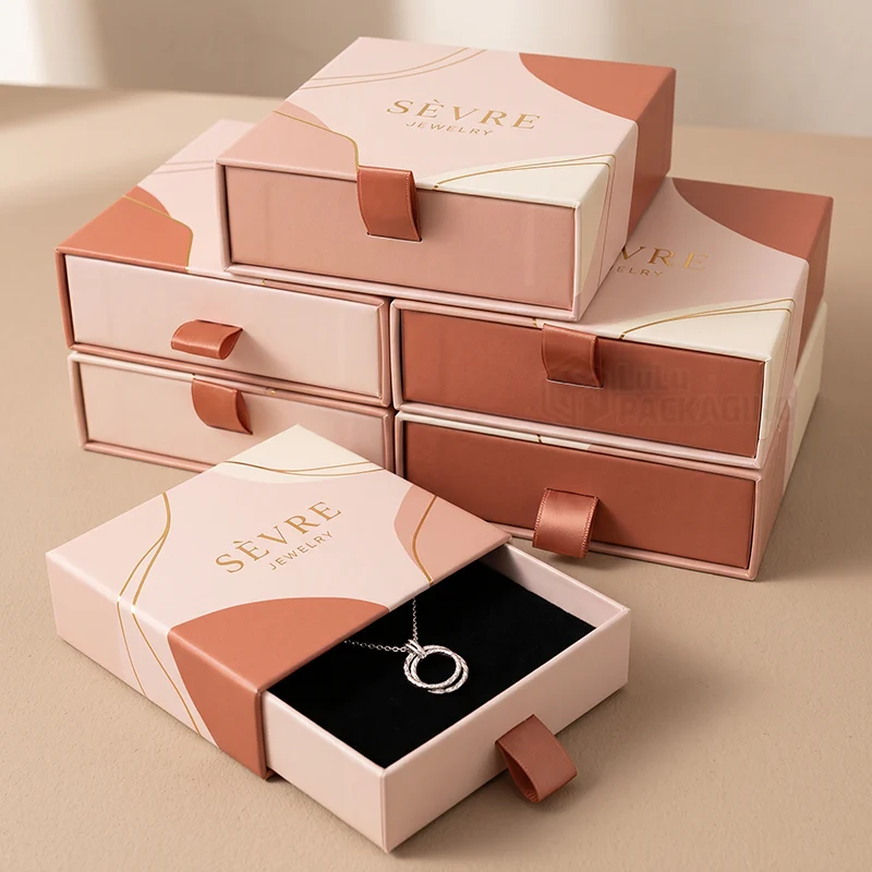 Stack of pink and terracotta jewellery gift drawer boxes, one open with a ring pendant necklace