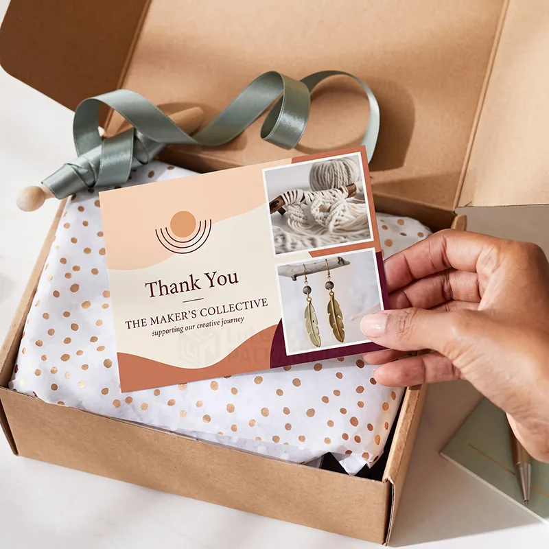 Hand placing a printed insert card with product photos onto dotted tissue paper in an open kraft mailer box