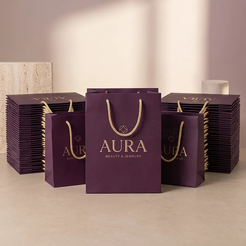 Stacks of purple paper retail bags with gold rope handles ready for a store opening