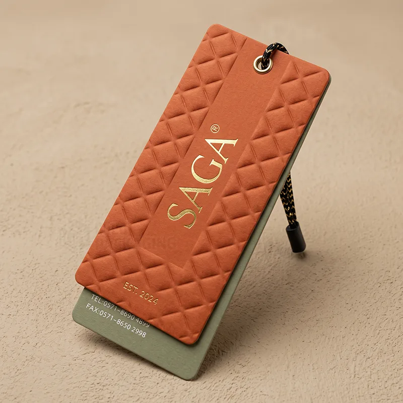 Orange quilted embossed hang tag with gold foil lettering, a metal eyelet and a gold cord, layered on a green card