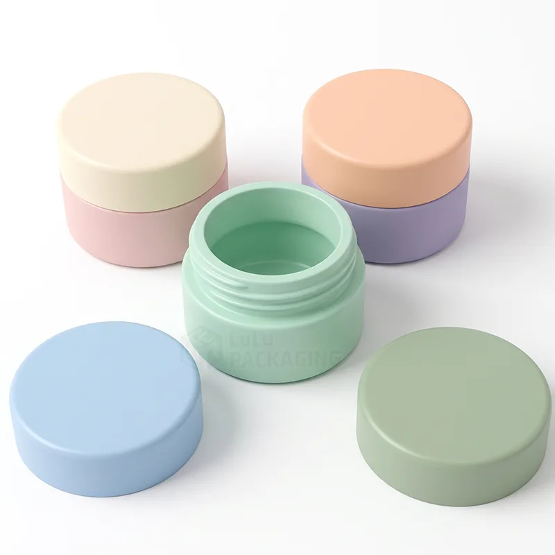 Empty open mint lip balm pot with blue and green lids beside closed pastel pots