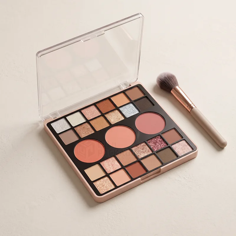 Open eyeshadow and blush palette case with a clear lid beside a makeup brush