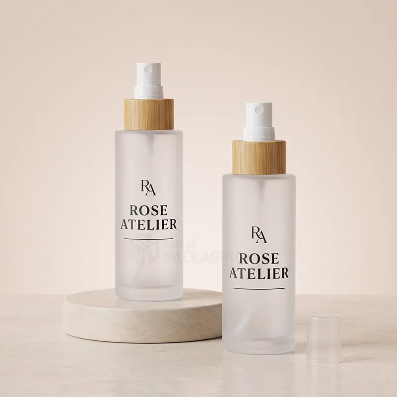 Two frosted glass spray bottles with bamboo collars and white sprayers