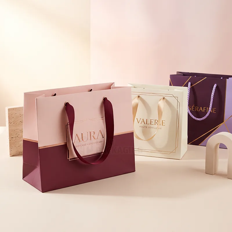 Pink, cream and purple paper gift bags with ribbon and rope handles and foil printed brand names
