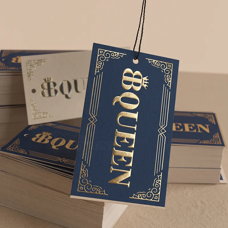 Navy hang tags with gold foil lettering and ornate gold borders, stacked with grey tags