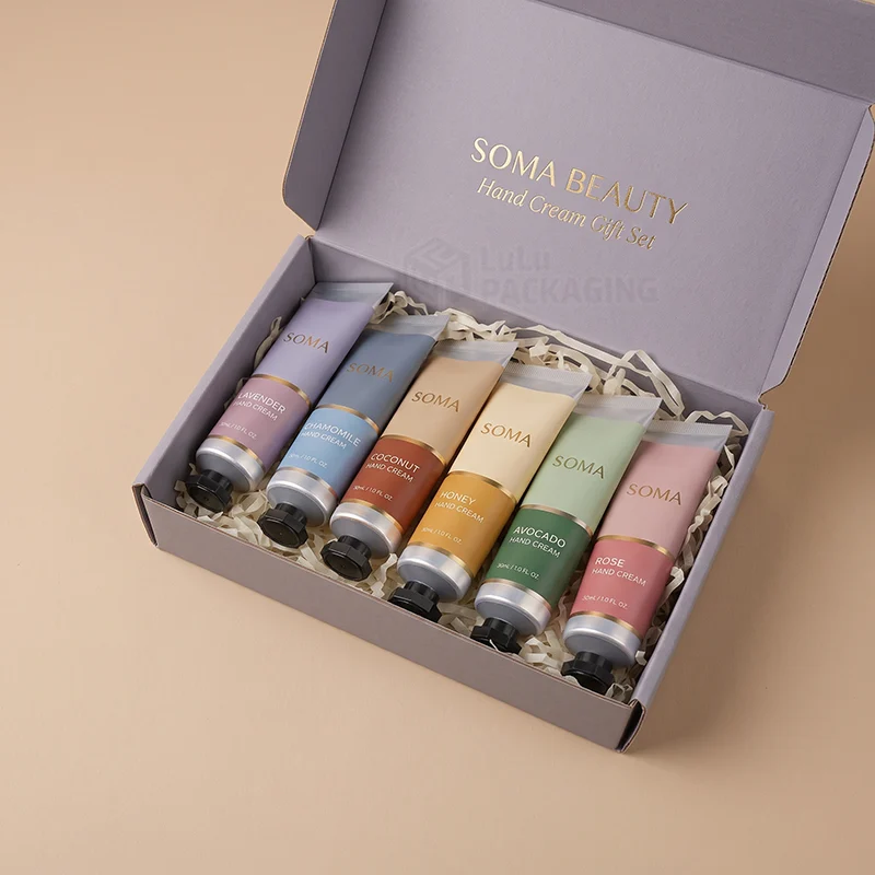 Lilac mailer box with gold foil text holding six coloured hand cream tubes