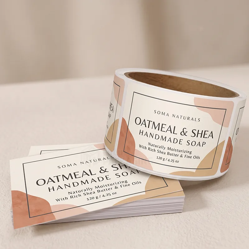 Roll and stack of rectangular oatmeal and shea soap labels with soft terracotta shapes