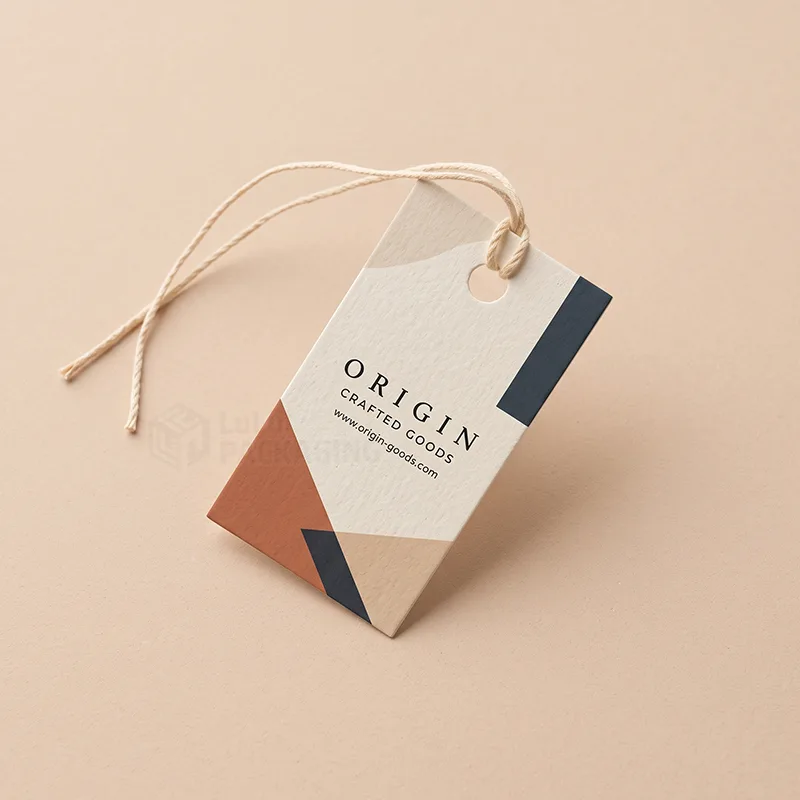 Cream hang tag with geometric colour blocks and a loose cotton string on a peach background