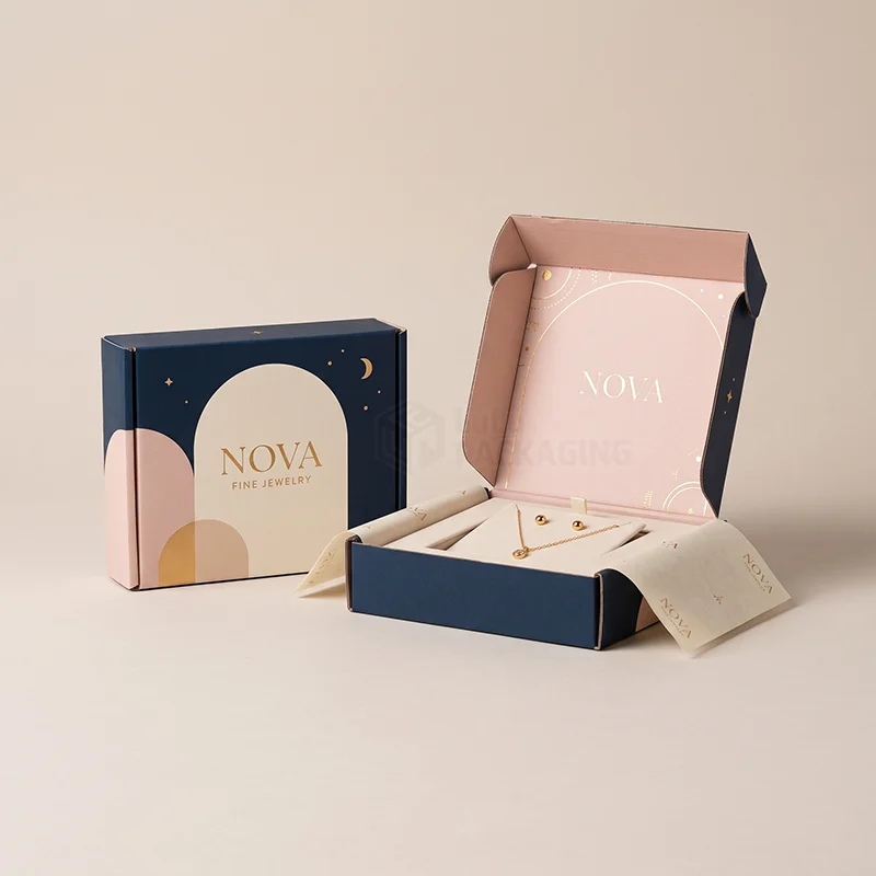 Navy and pink jewellery mailer boxes, one open showing a necklace and studs in a fitted insert