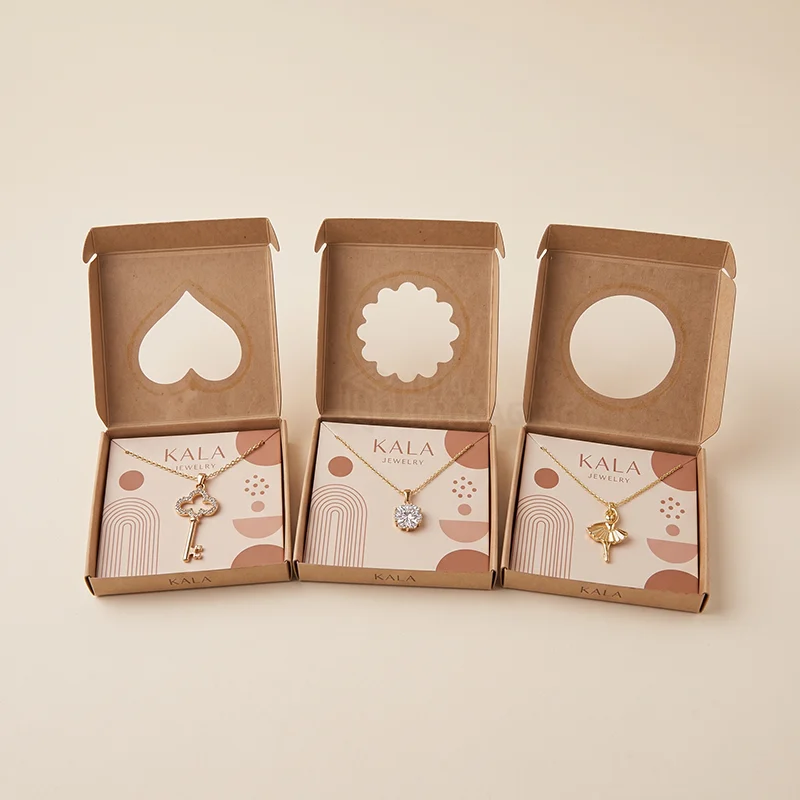 Three open kraft jewellery boxes with heart, flower and round cut-outs and pendant cards