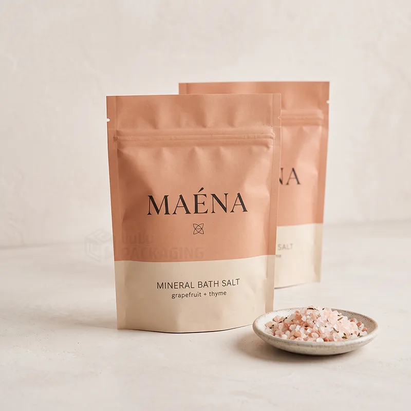 Kraft style stand up pouches with a zipper holding mineral bath salt beside a dish of pink salt