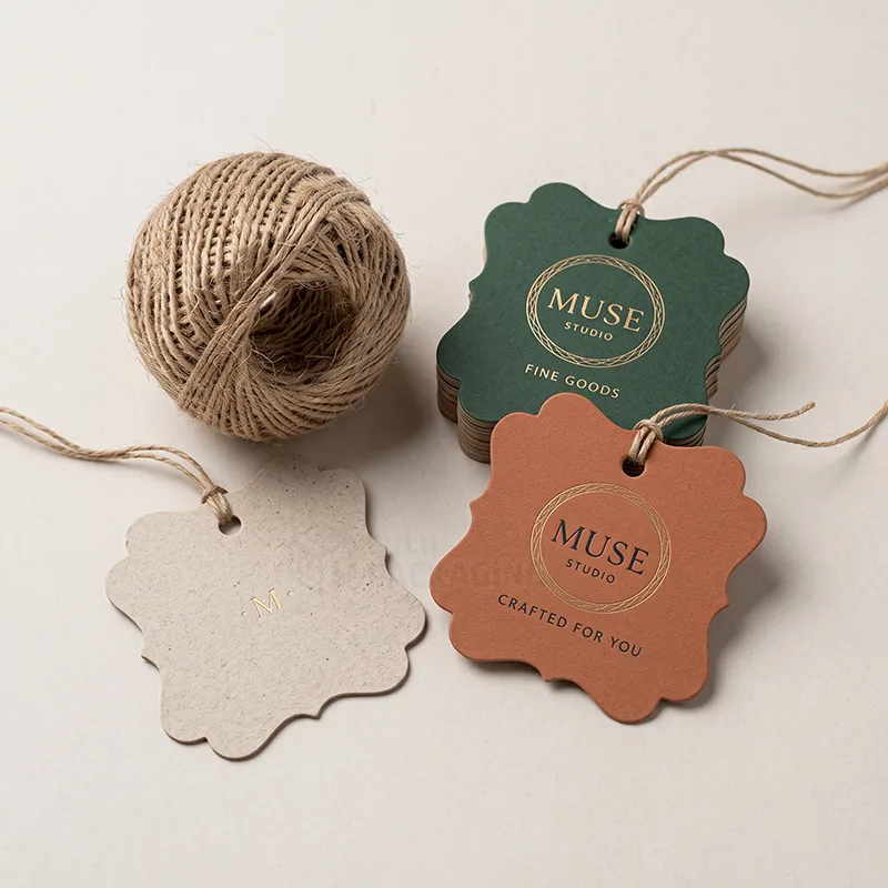 Scalloped tags with gold foil logos and a ball of jute twine, including a natural kraft tag