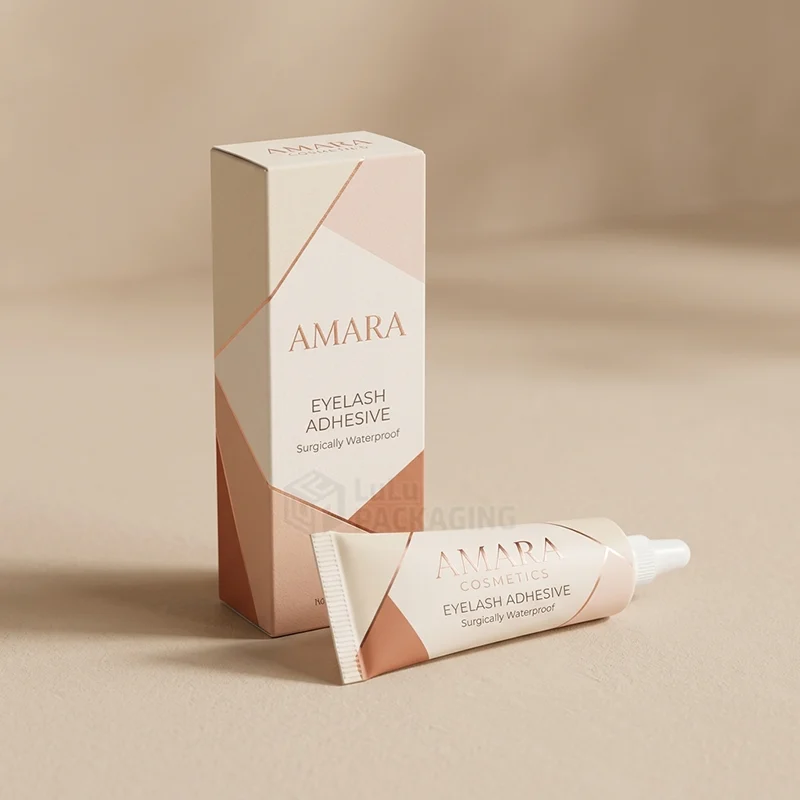 Tall blush lash glue box with rose gold geometric print beside a matching tube