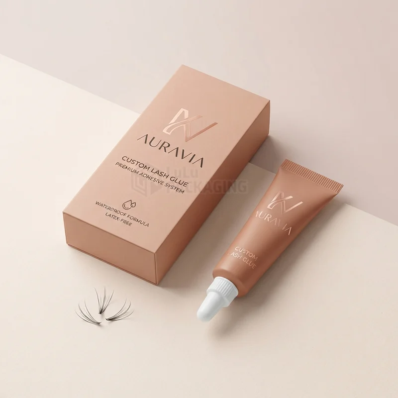 Copper lash glue box with foil logo beside a glue tube and loose lash fans