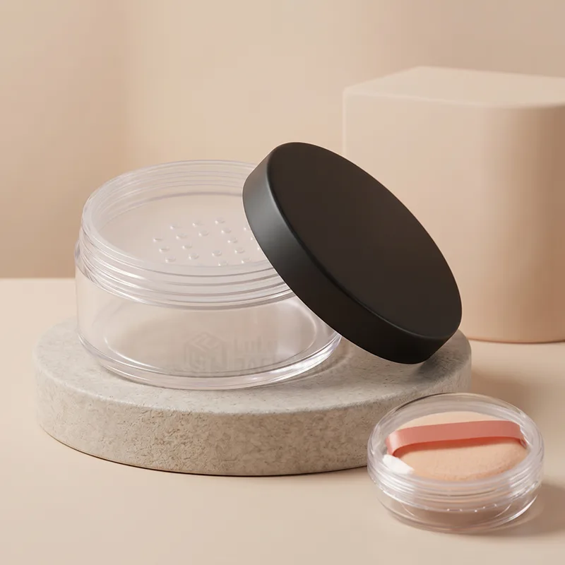 Clear loose powder jar with a matte black lid and sifter holes, beside a mini jar with a puff