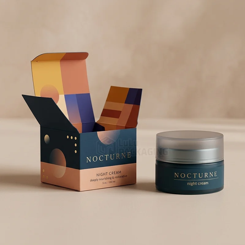 Open tuck end night cream box with colourful inside print next to a dark blue jar