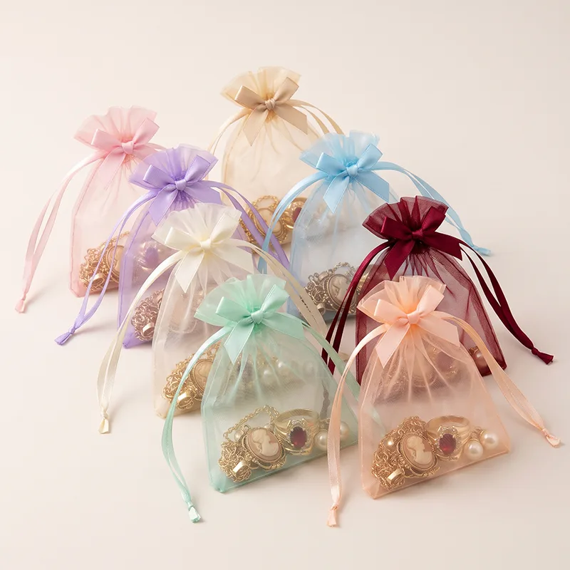 Pastel organza bags tied with satin bows holding vintage rings and brooches