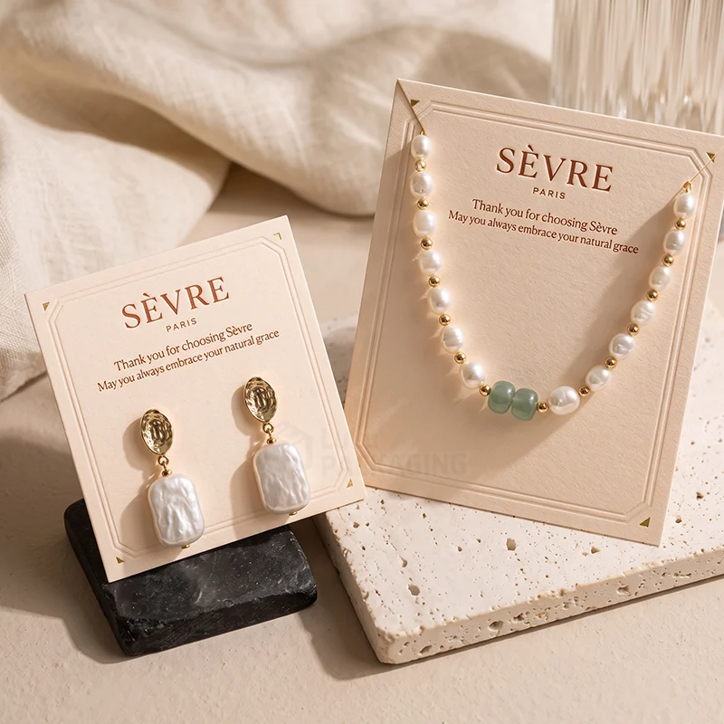 Cream necklace card with a pearl necklace beside a matching earring card with pearl drops