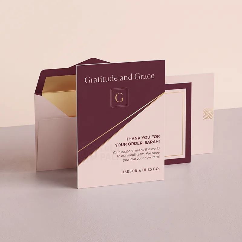 Personalised plum and blush insert card with gold foil lines standing in front of a gold-lined envelope