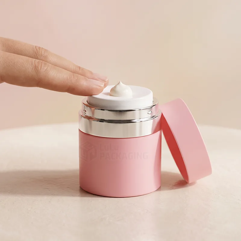 Pink airless jar with its lid off and cream dispensed on the white pump head