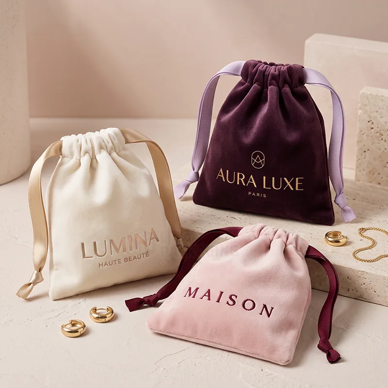 Small velvet drawstring bags with satin ribbon ties beside gold earrings