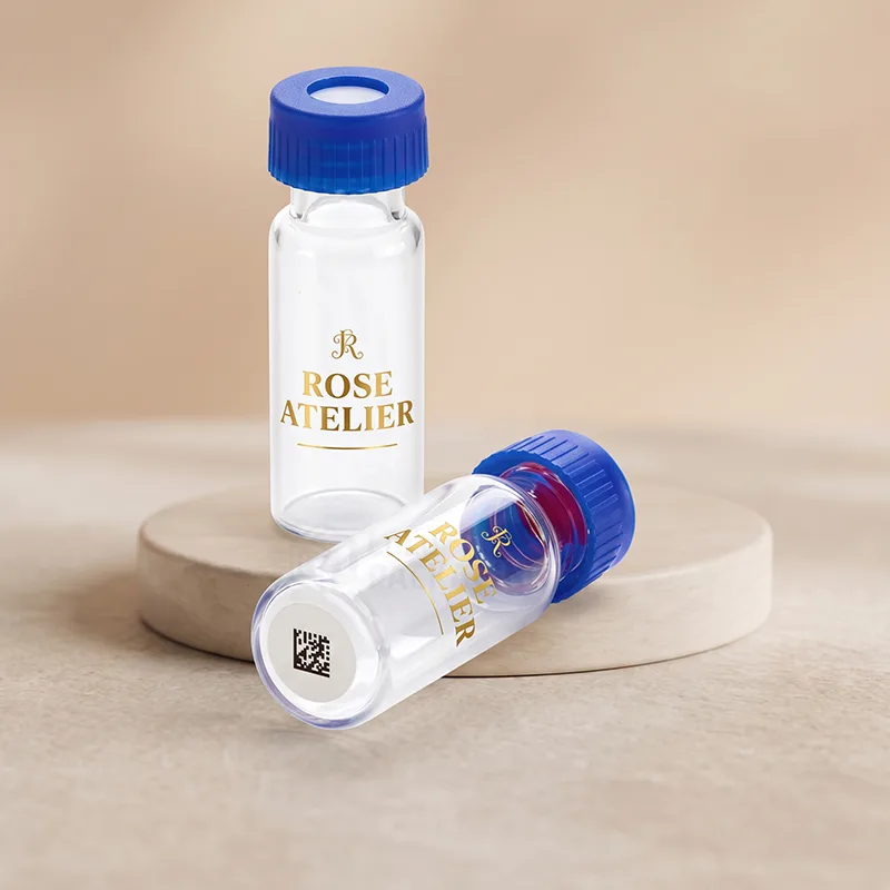Two small clear glass vials with blue screw caps and gold printed logos