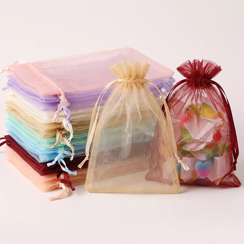 Stack of flat organza drawstring bags in many colours beside gold and burgundy bags