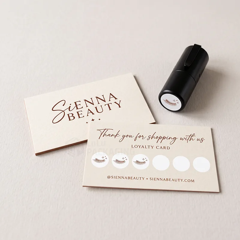 Cream loyalty card with three eyelash stamps in a row of circles beside a self-inking stampe