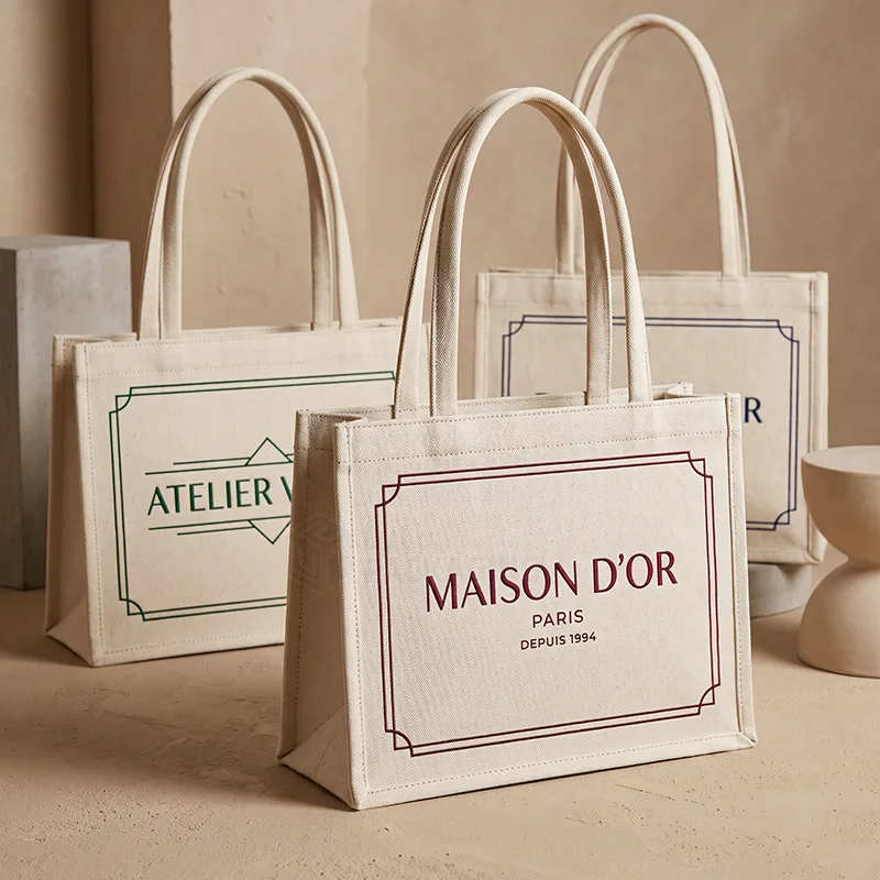 Boxy natural canvas tote bags with short handles and a printed framed logo