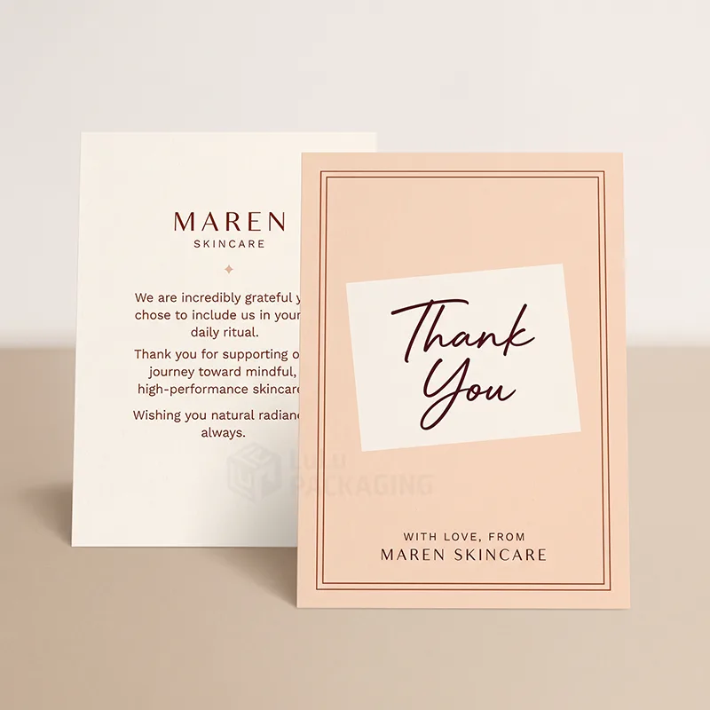 Peach thank you card with script lettering standing beside a cream card printed with a thank you message