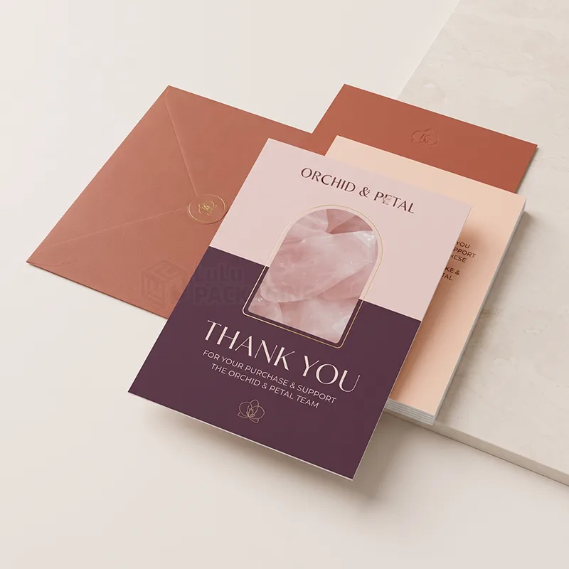 Plum and blush thank you card with arched photo window, laid over a terracotta envelope and spare cards