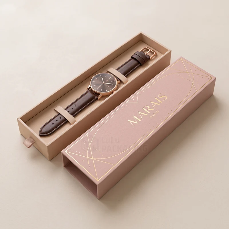 Long drawer watch box with a foil-printed pink sleeve and a brown leather watch inside
